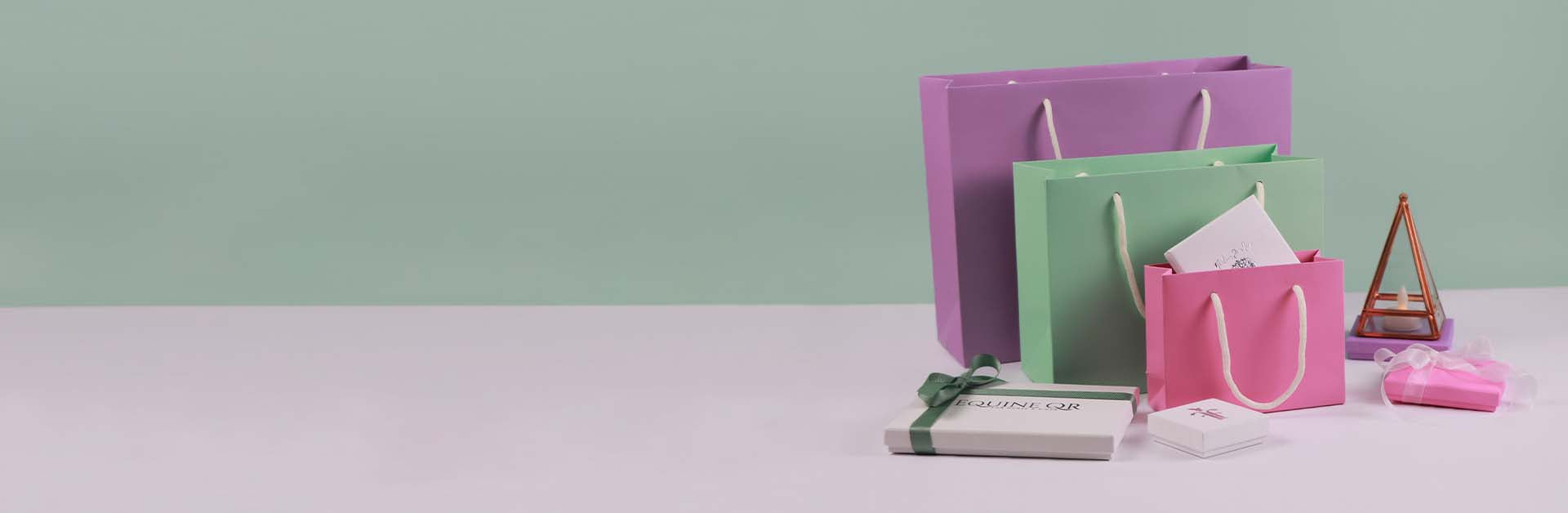 Colorful gift bags on a light purple surface with a green background