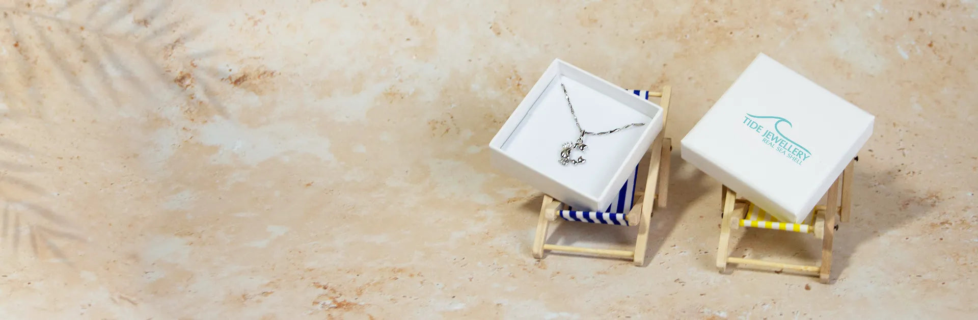 A silver necklace with a dolphin pendant in a white gift box labelled 