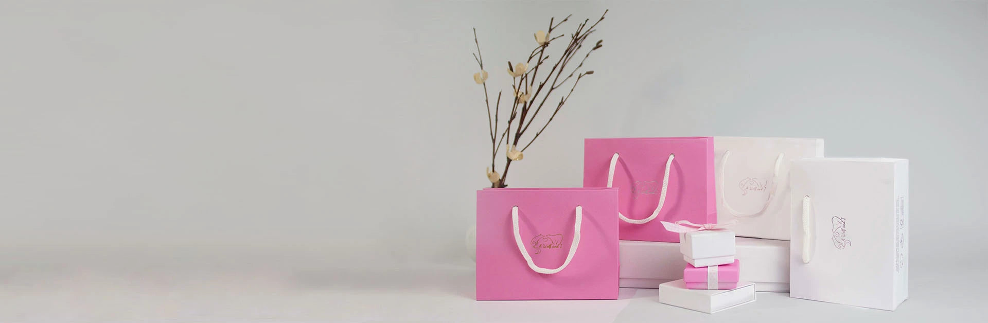 Pink and white shopping bags with white handles are placed against a light grey background.