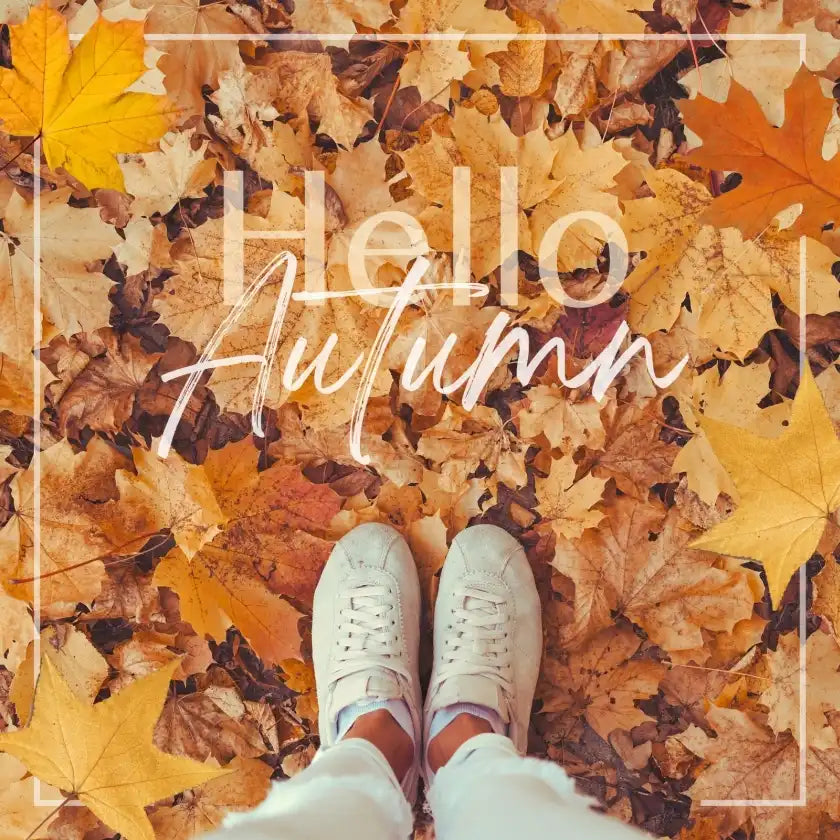 White sneakers on a bed of autumn leaves with 'Hello Autumn' text.