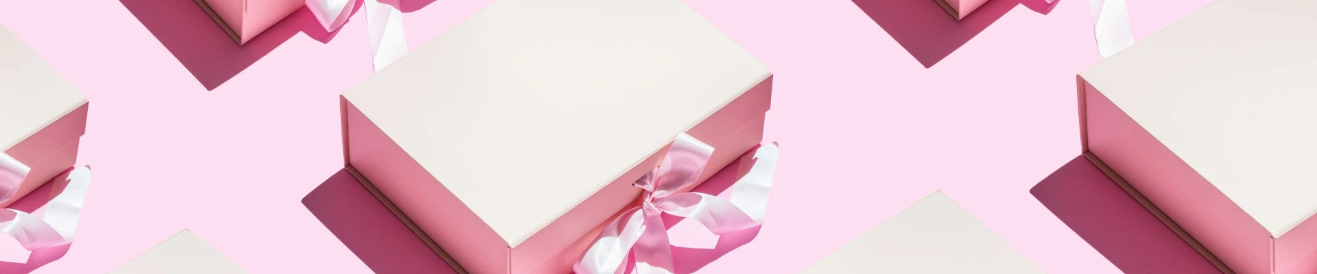 Multiple pink gift boxes, decorated with a pink bow, on a pink background.