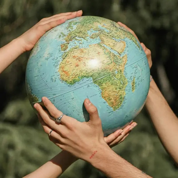 Two hands holding a globe with a blurred green background