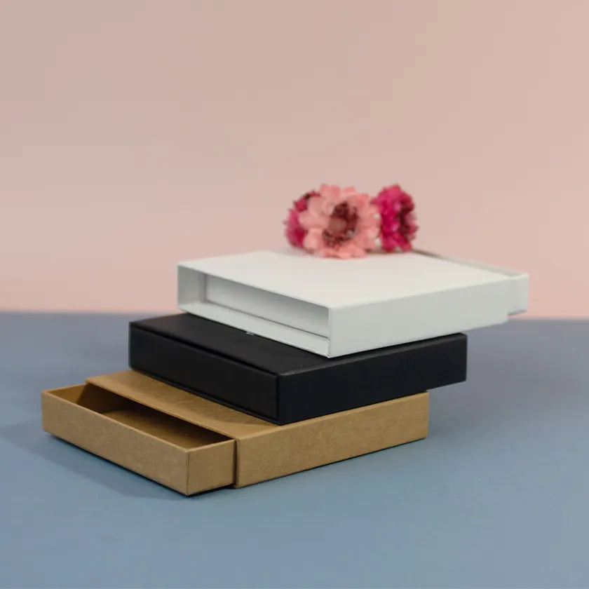 Stacked matchboxes in brown, black, and white on a blue surface.