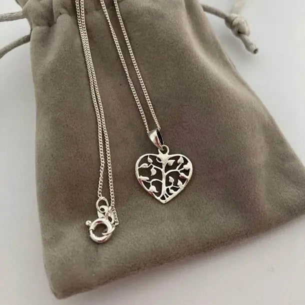 Silver necklace with a heart-shaped pendant on a soft grey fabric pouch