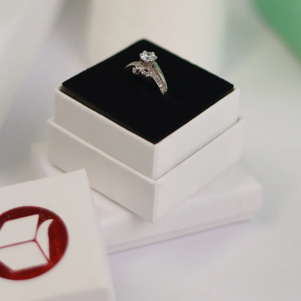 Diamond ring on a black cushion in a white box with a blurred background