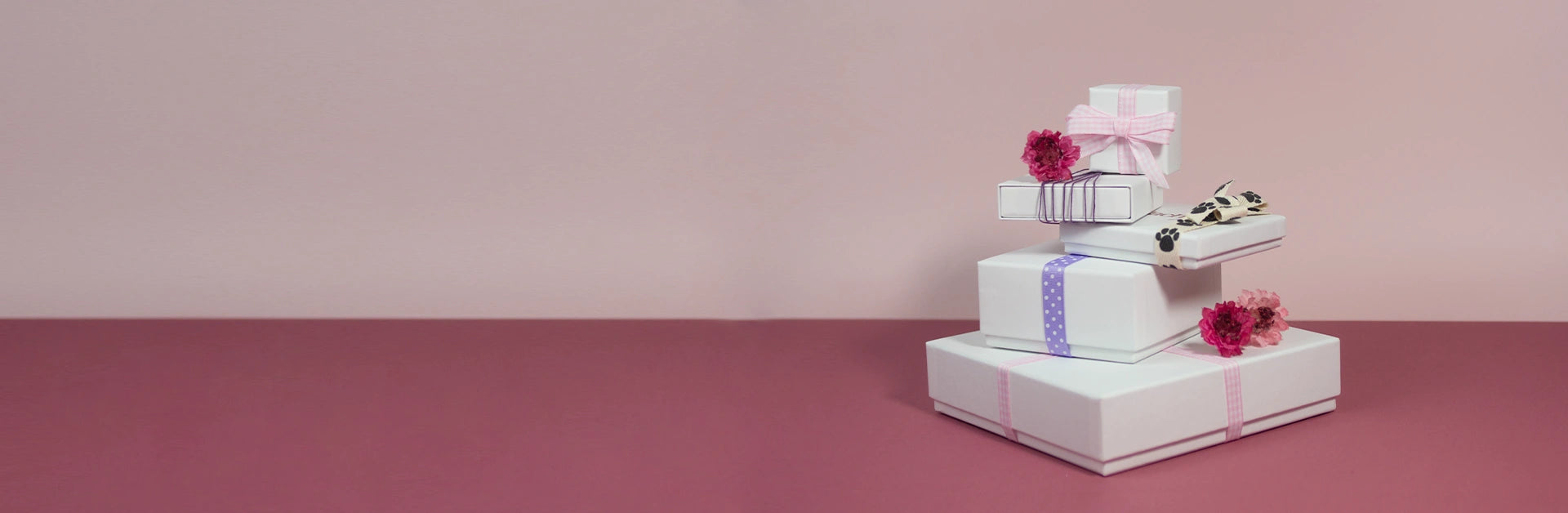 Neatly stacked white boxes adorned with pink ribbons, creating an elegant gift display.